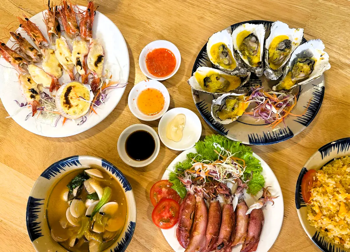 Table seen from above with grilled oysters, prawns, squid and clam soup