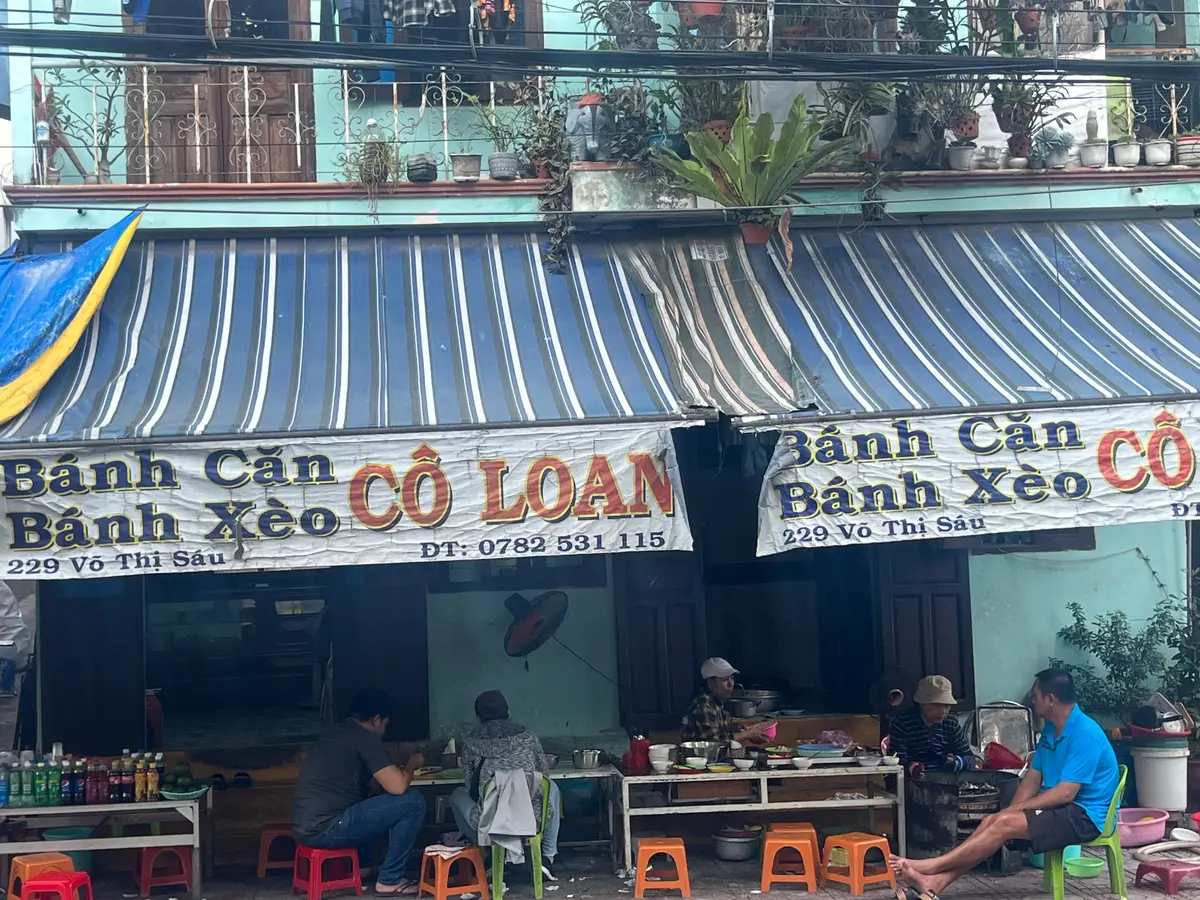 Open-fronted shop with a blue striped awning and a sign for rice pancakes and savoury pancakes