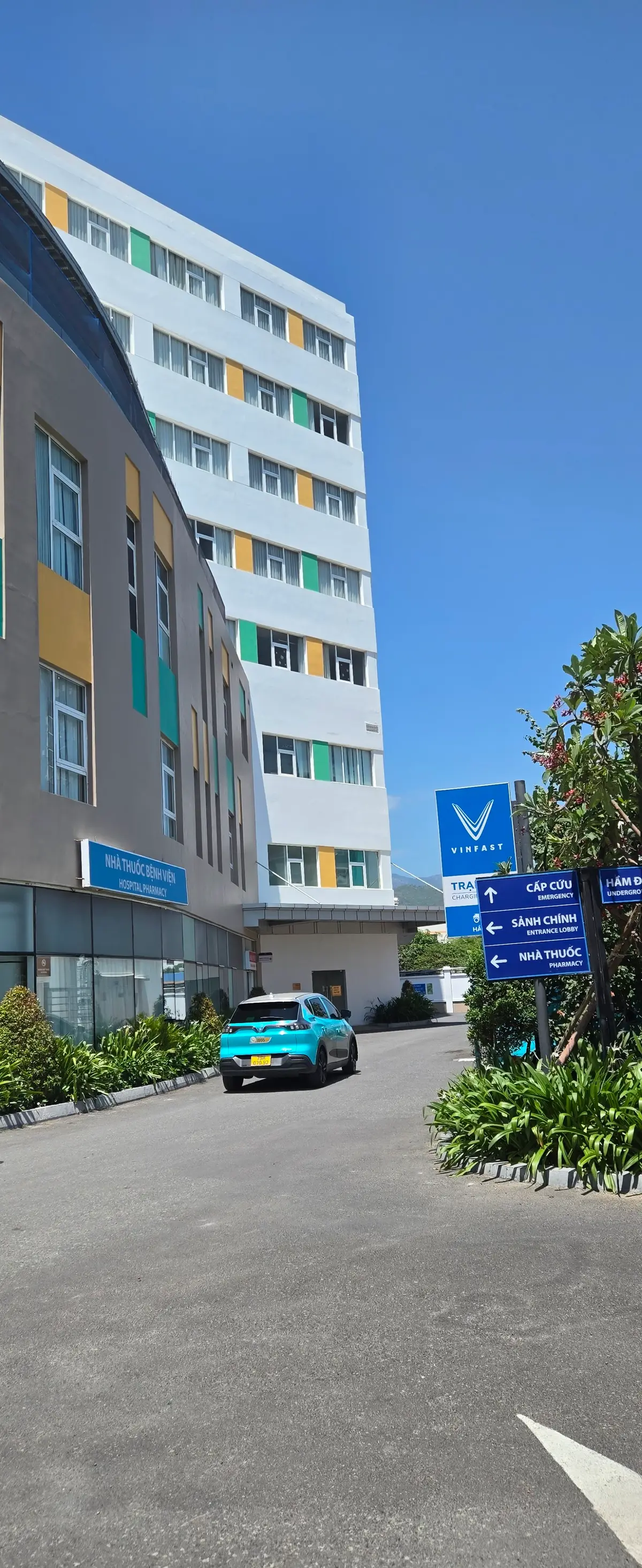 Vinmec Nha Trang hospital building with a blue emergency direction sign, a pharmacy sign and a car park