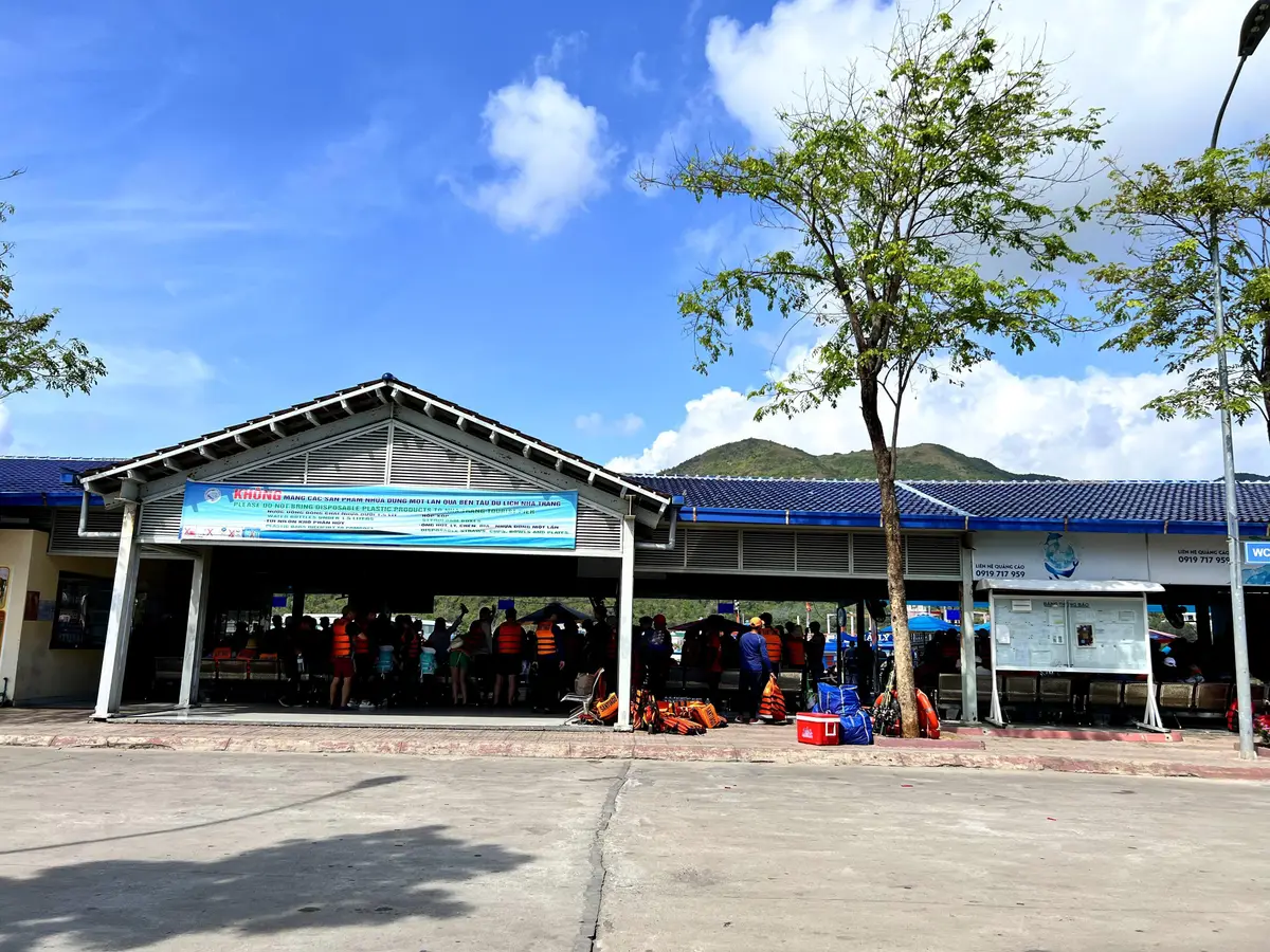 Nha Trang tourist pier at Cau Da with a low terminal building, blue roofs and an open forecourt under a blue sky